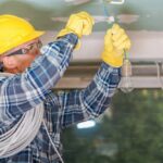 Elektricien plaatst een verlichtingsarmatuur aan het plafond