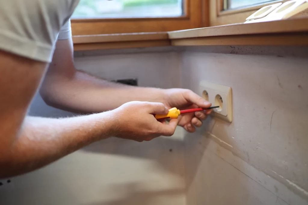 Elektricien schroeft een stopcontact vast in een woning in Zottegem