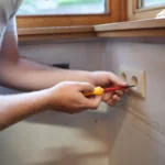 Elektricien schroeft een stopcontact vast in een woning in Zottegem
